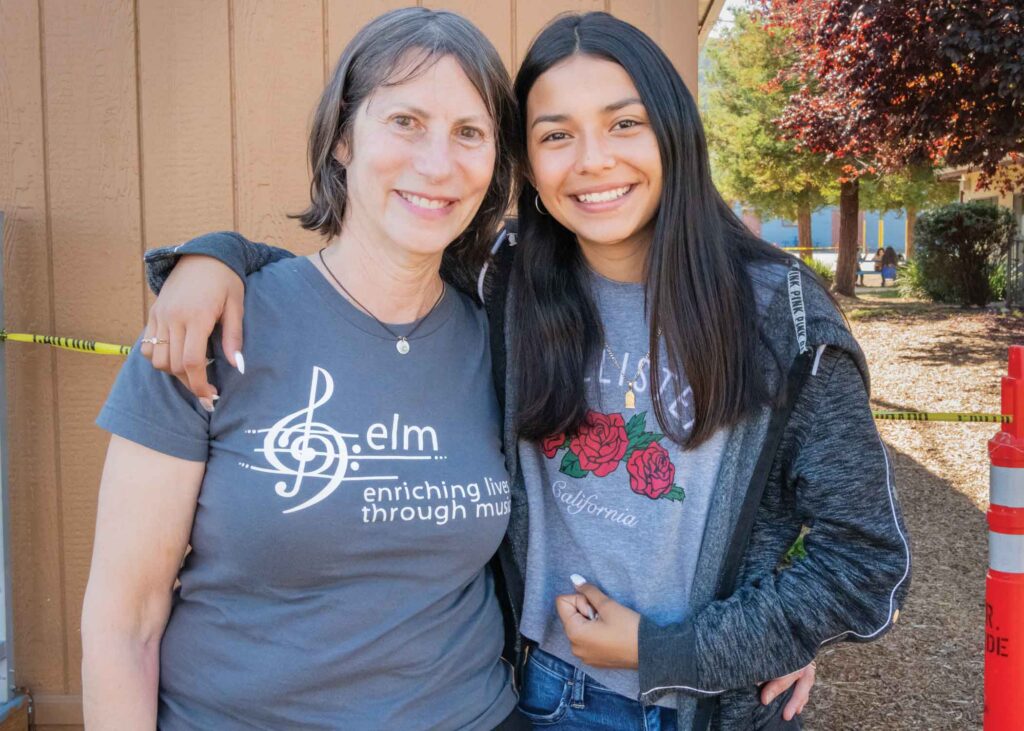 Jane Kramer of Enriching Lives through Music smiling with student