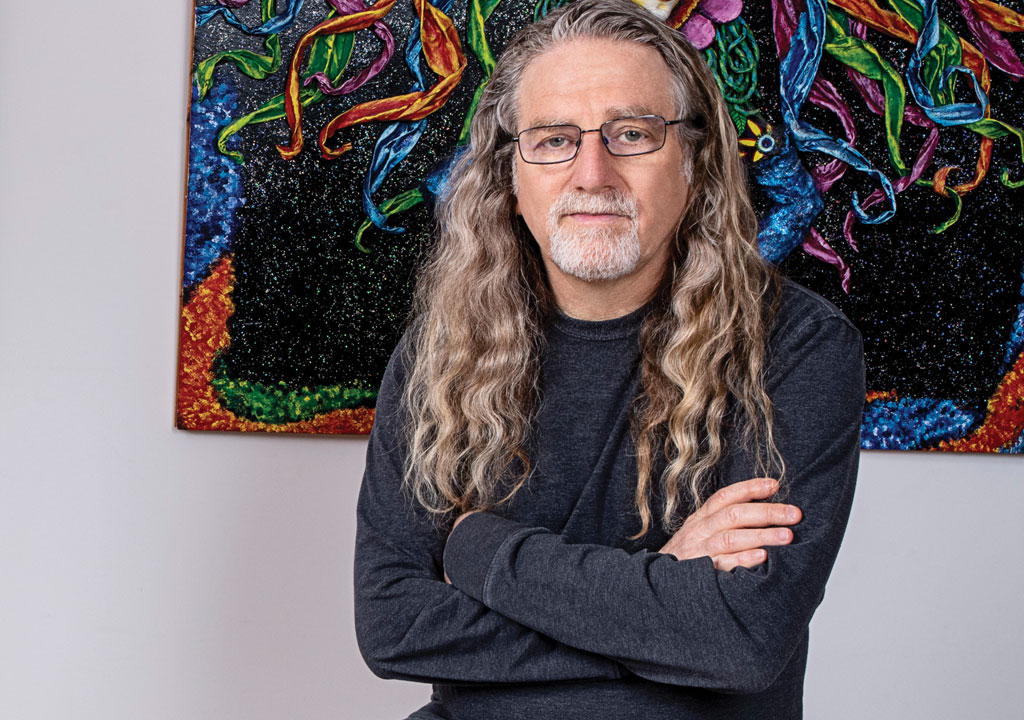 music photographer Jay Blakesberg sitting in front of psychedelic art