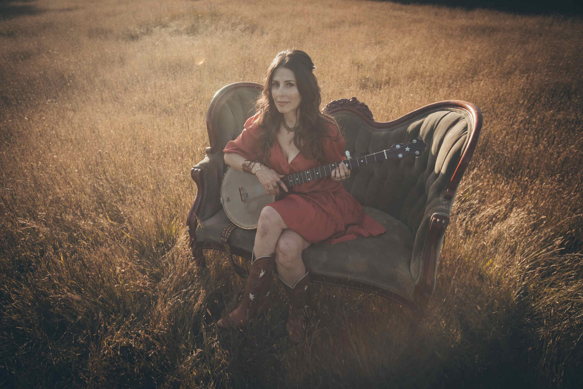 Essence Goldan sitting in a field with a guitar