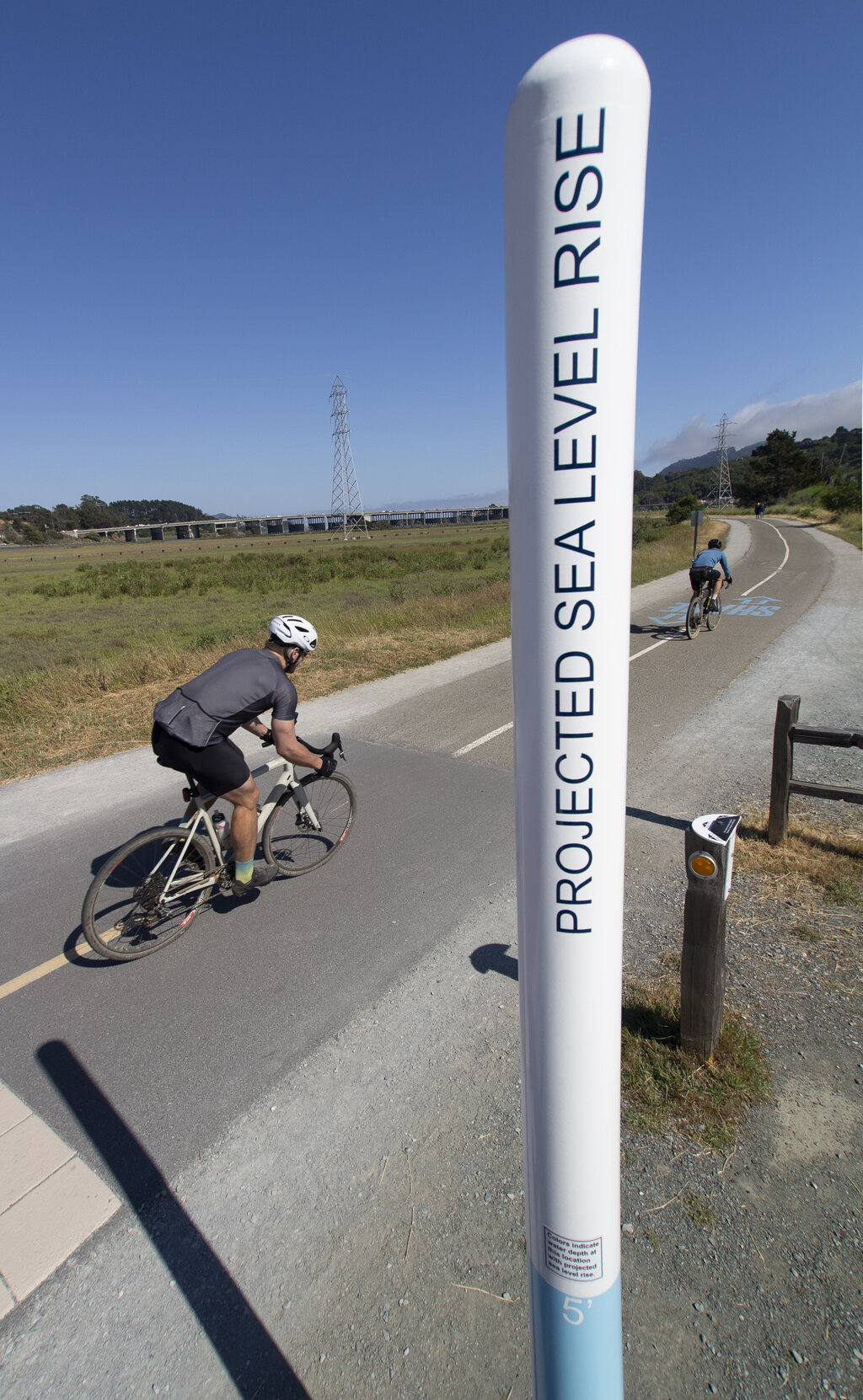 bicyclist rides past sea level sign