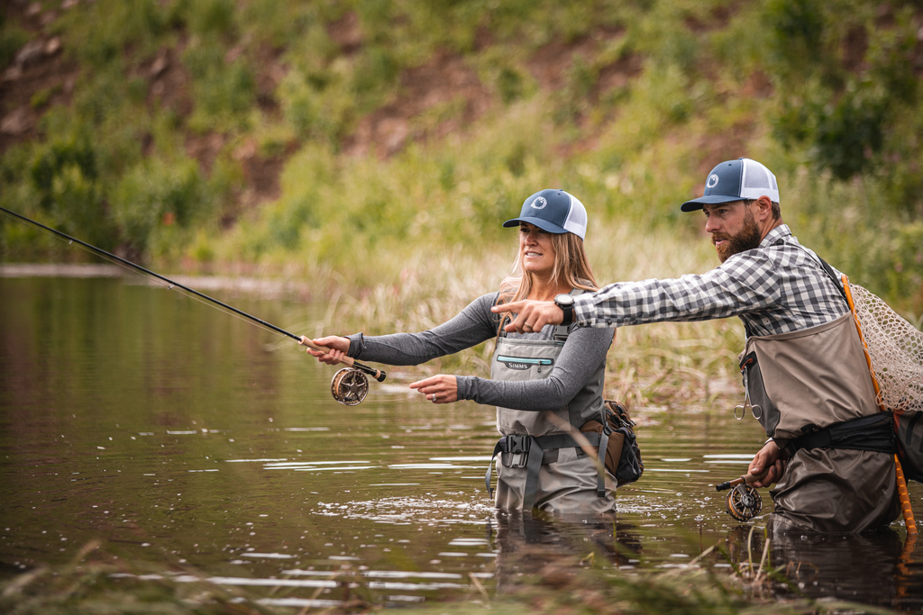 a man and woman fly fishing in a river