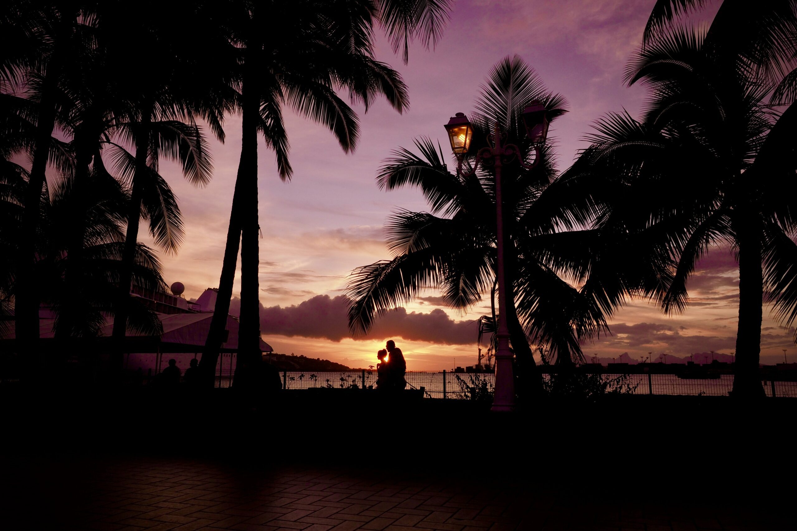 a couple walks in front of a sunset in Tahiti