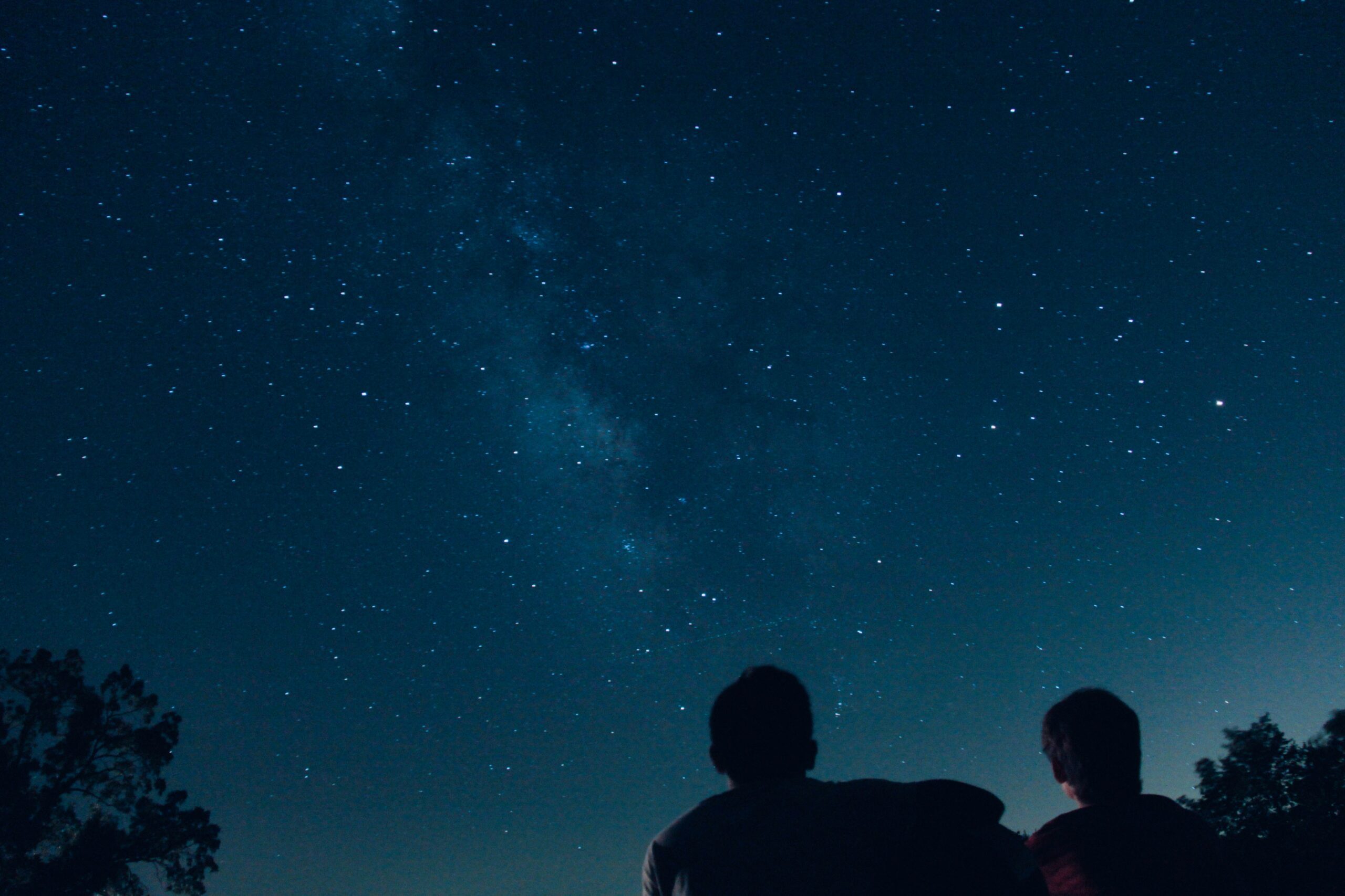 two stargazers look at the night sky