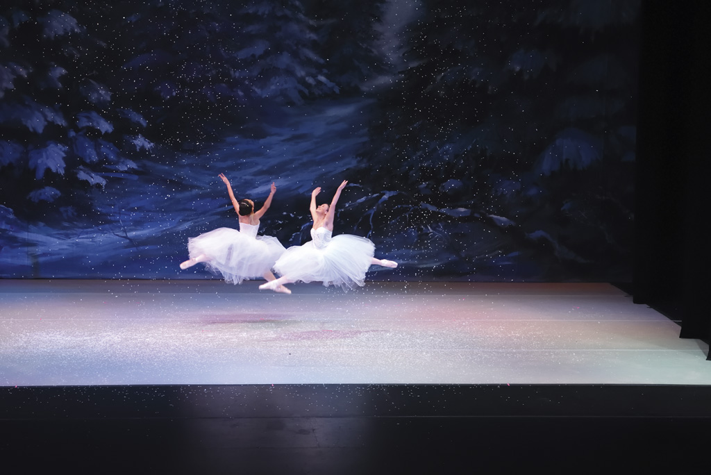 two ballet dancers leaping during a Nutcracker performance