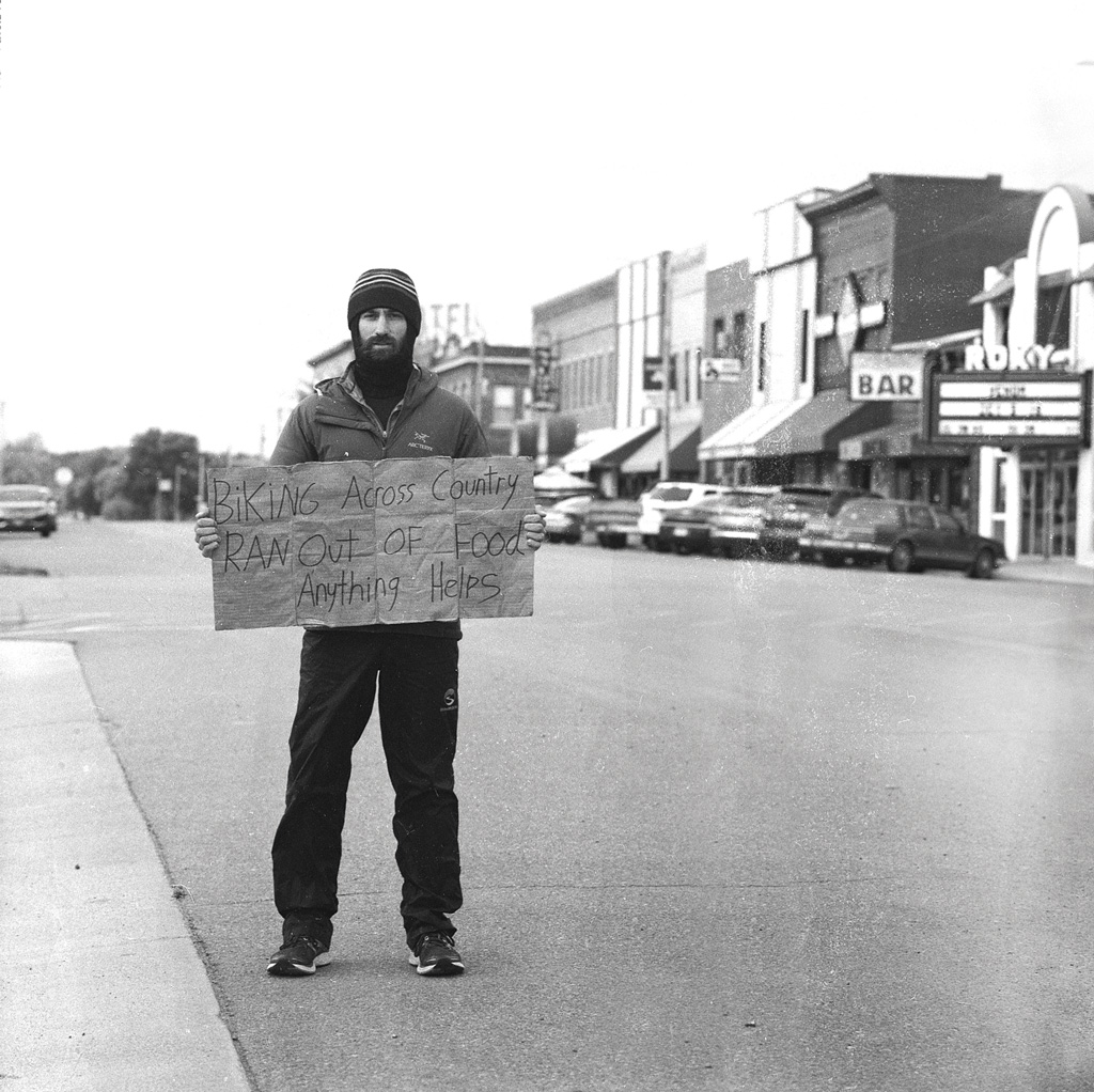 Daniel Troia holding a sign on his bicycle trip