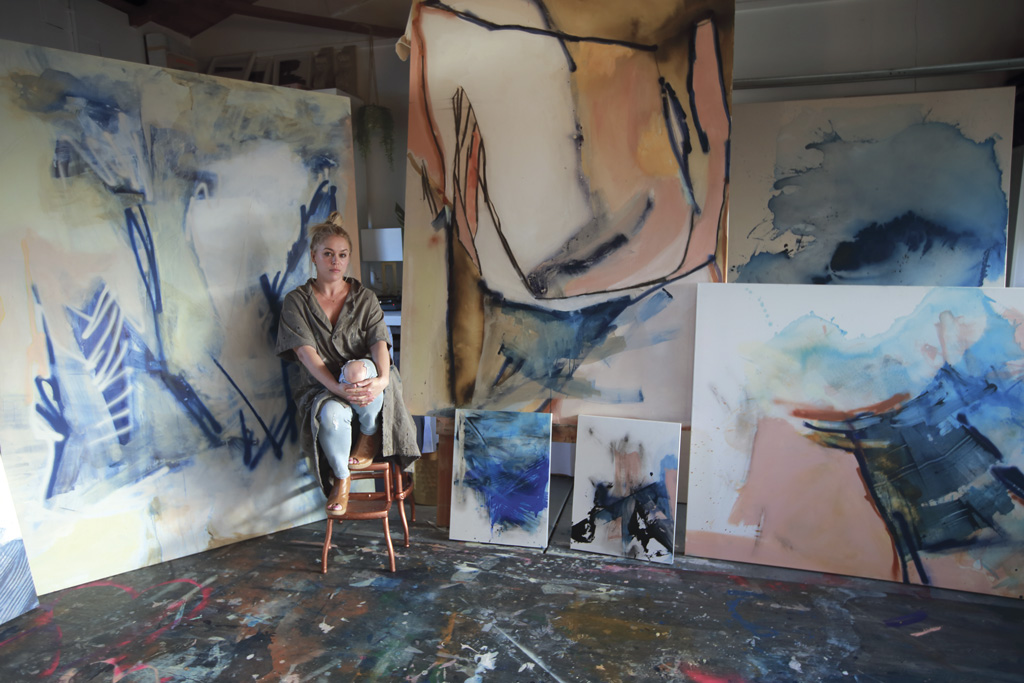 artist Ellie Fritz next to her paintings